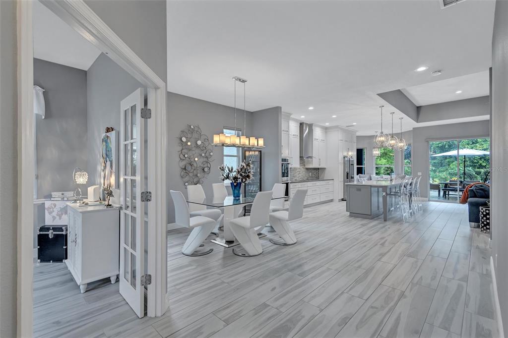 An open-concept dining area and kitchen feature gray tile floors, white cabinetry, and modern lighting — 139 TALL TREES COURT, SARASOTA, FL