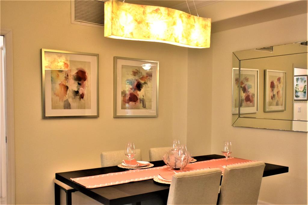 A dining room features a dark table, upholstered chairs, abstract wall art, and a rectangular light — 12500 GHIBERTI CIRCLE UNIT 102, VENICE, FL