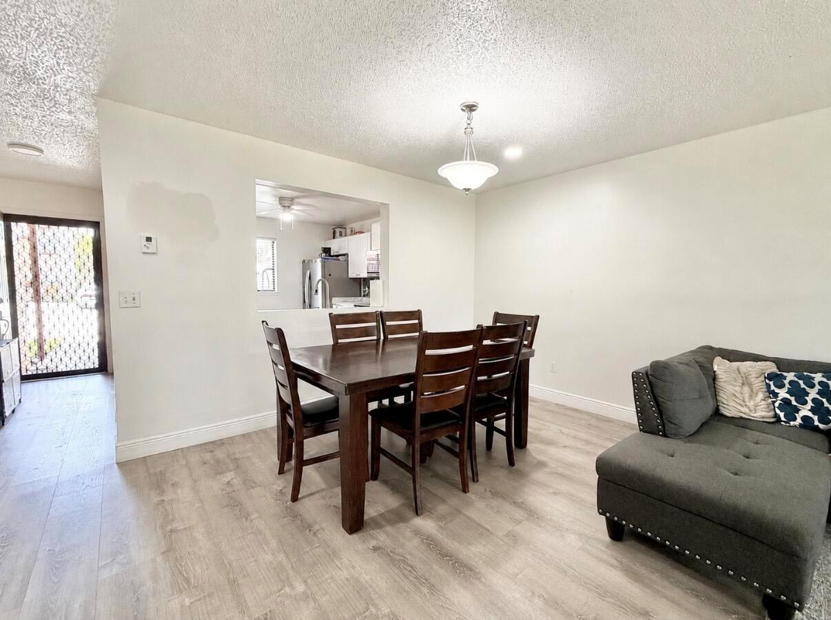 A dining area with a wooden table and chairs sits adjacent to a living room — 1407 E Lakeview Dr Drive E, Royal Palm Beach FL 33411, ROYAL PALM BEACH, FL