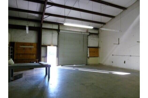 An interior view of a warehouse space featuring a concrete floor and a roll-up door — 820 35th Court SW, Vero Beach FL 32968, VERO BEACH, FL