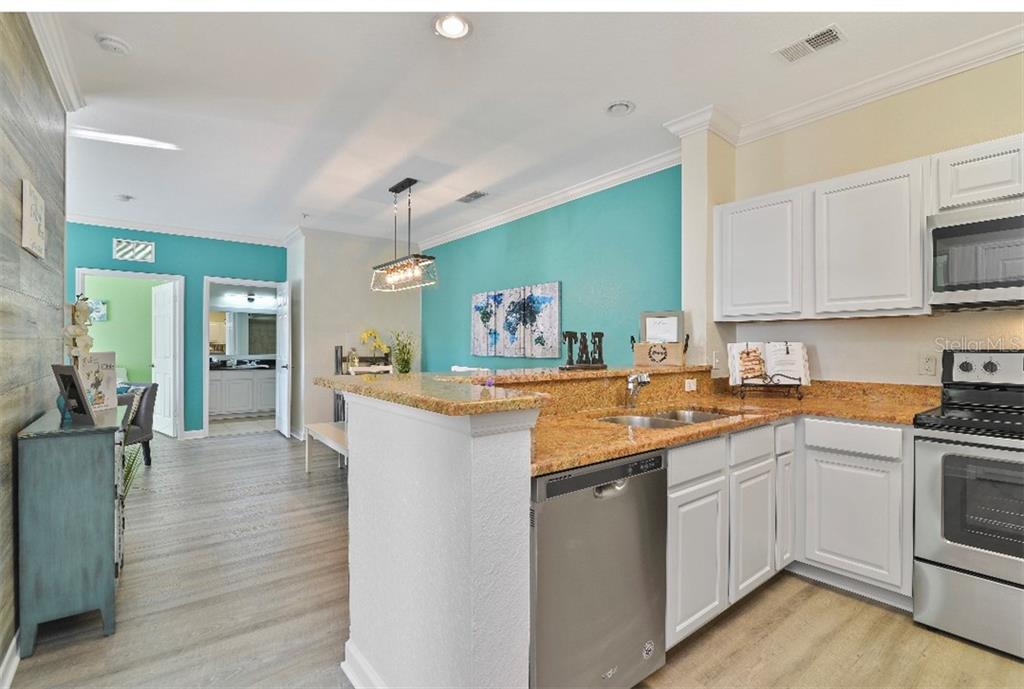 A kitchen with white cabinets, granite countertops, and a teal accent wall in the dining area — 1301 TUSCAN TERRACE UNIT 9407, DAVENPORT, FL