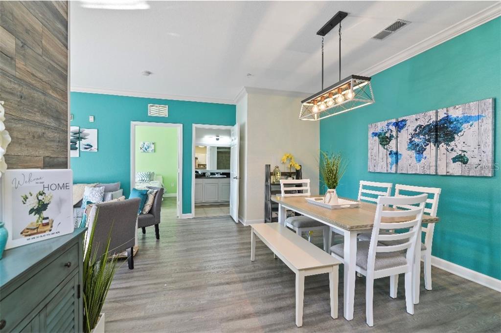 A dining area with a wooden table, white chairs, and a turquoise accent wall — 1301 TUSCAN TERRACE UNIT 9407, DAVENPORT, FL