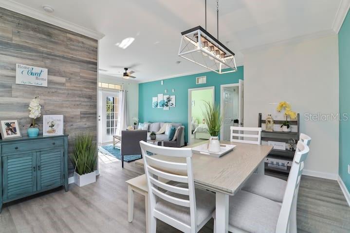 A dining area with a wooden table and chairs sits before a living room with teal walls — 1301 TUSCAN TERRACE UNIT 9407, DAVENPORT, FL