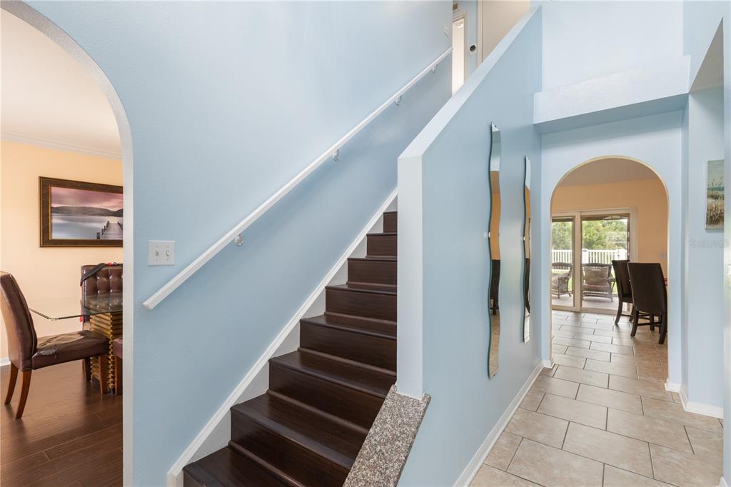An entryway features a dark wood staircase, light blue walls, and a tiled hallway — 17017 TORVEST COURT, LAND O LAKES, FL