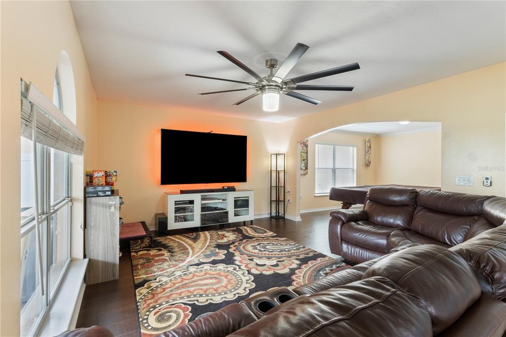 A living room features a large television, a leather sectional, and a patterned area rug — 17017 TORVEST COURT, LAND O LAKES, FL