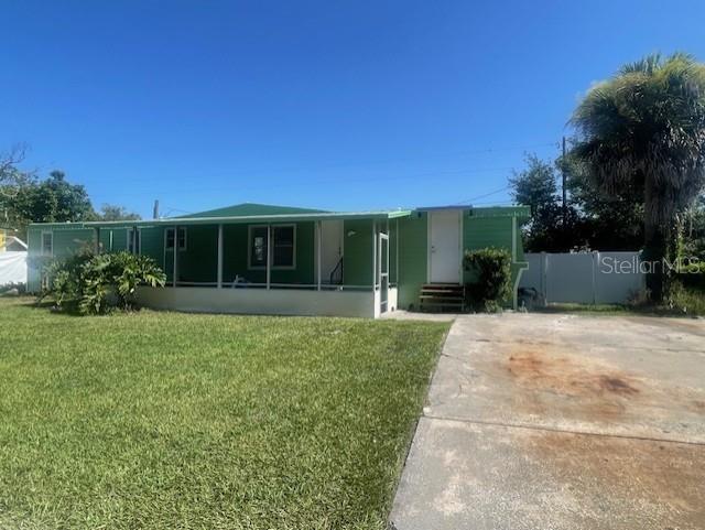 A light green mobile home with a screened-in porch sits on a grassy lot — 7489 CHARLIN PARKWAY, ORLANDO, FL