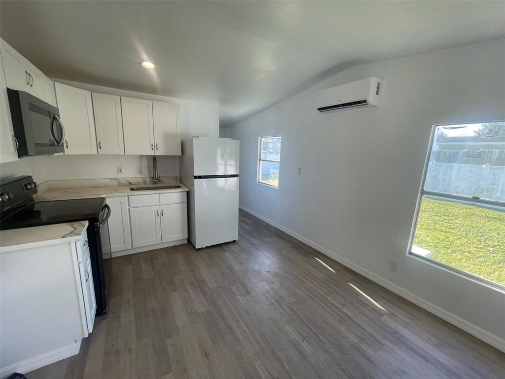 A kitchen with white cabinets, stainless steel appliances, and light wood-look flooring — 7489 CHARLIN PARKWAY, ORLANDO, FL
