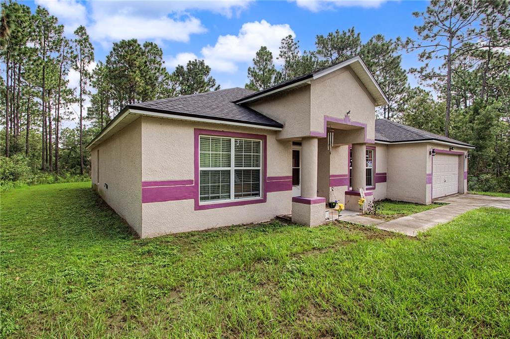 A single-story house with beige stucco walls, purple trim, and a two-car garage — 8137 SW 138TH STREET ROAD, OCALA, FL