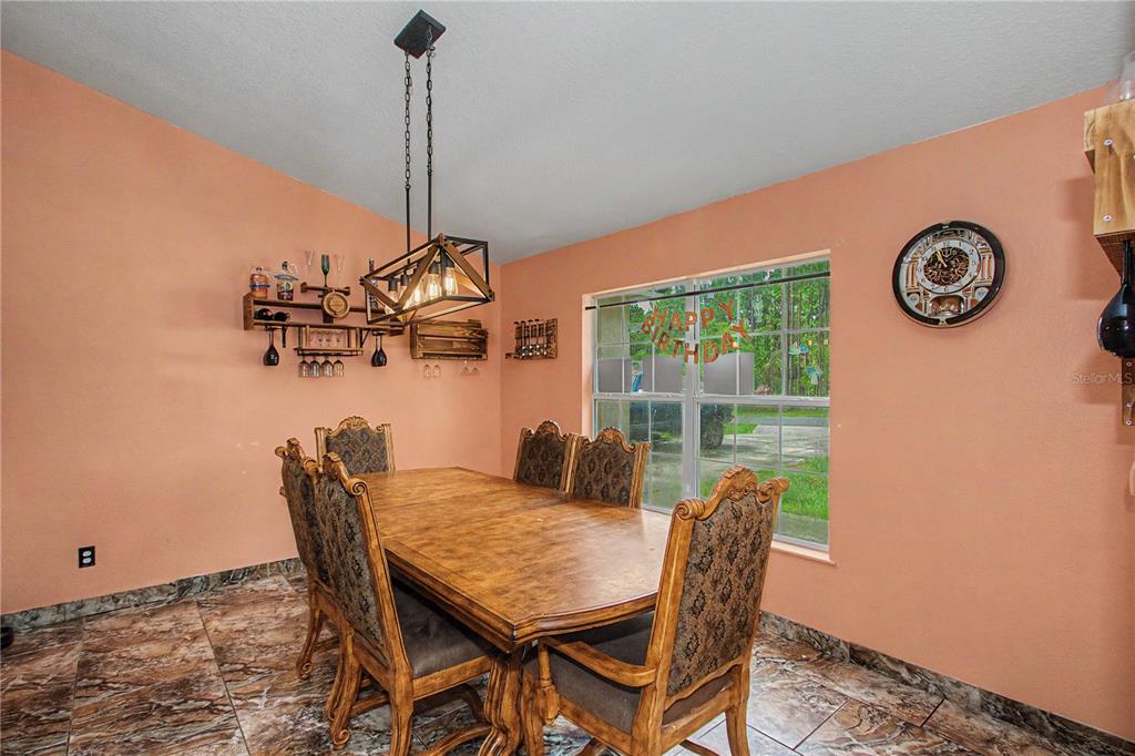 A dining room features a wooden table, upholstered chairs, a hanging light, and peach walls — 8137 SW 138TH STREET ROAD, OCALA, FL