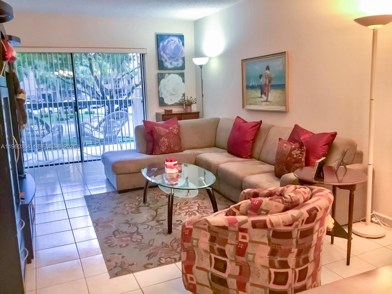A living room features a sectional sofa, patterned armchair, glass coffee table, and sliding doors — 5800 SW 127th Ave # 2220, Miami FL 33183, MIAMI, FL