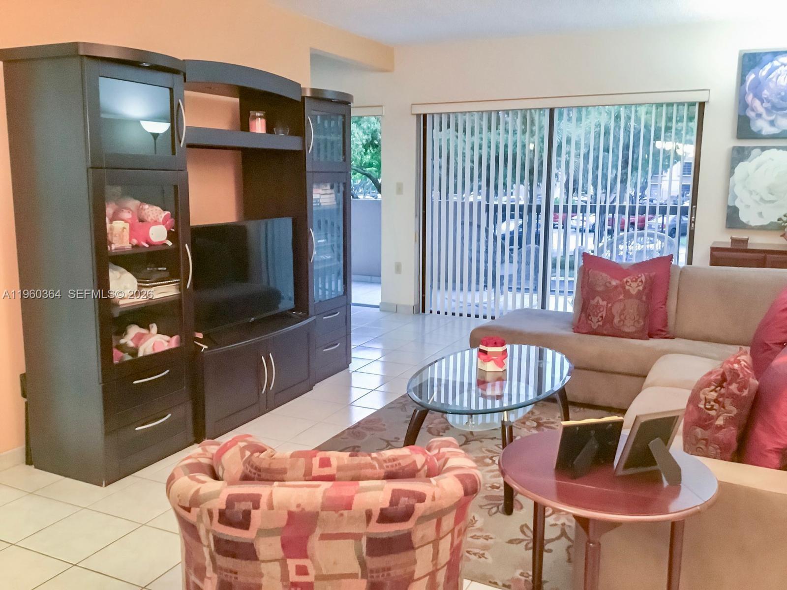 A living room features a dark entertainment center, a sectional sofa, and a glass coffee table — 5800 SW 127th Ave # 2220, Miami FL 33183, MIAMI, FL