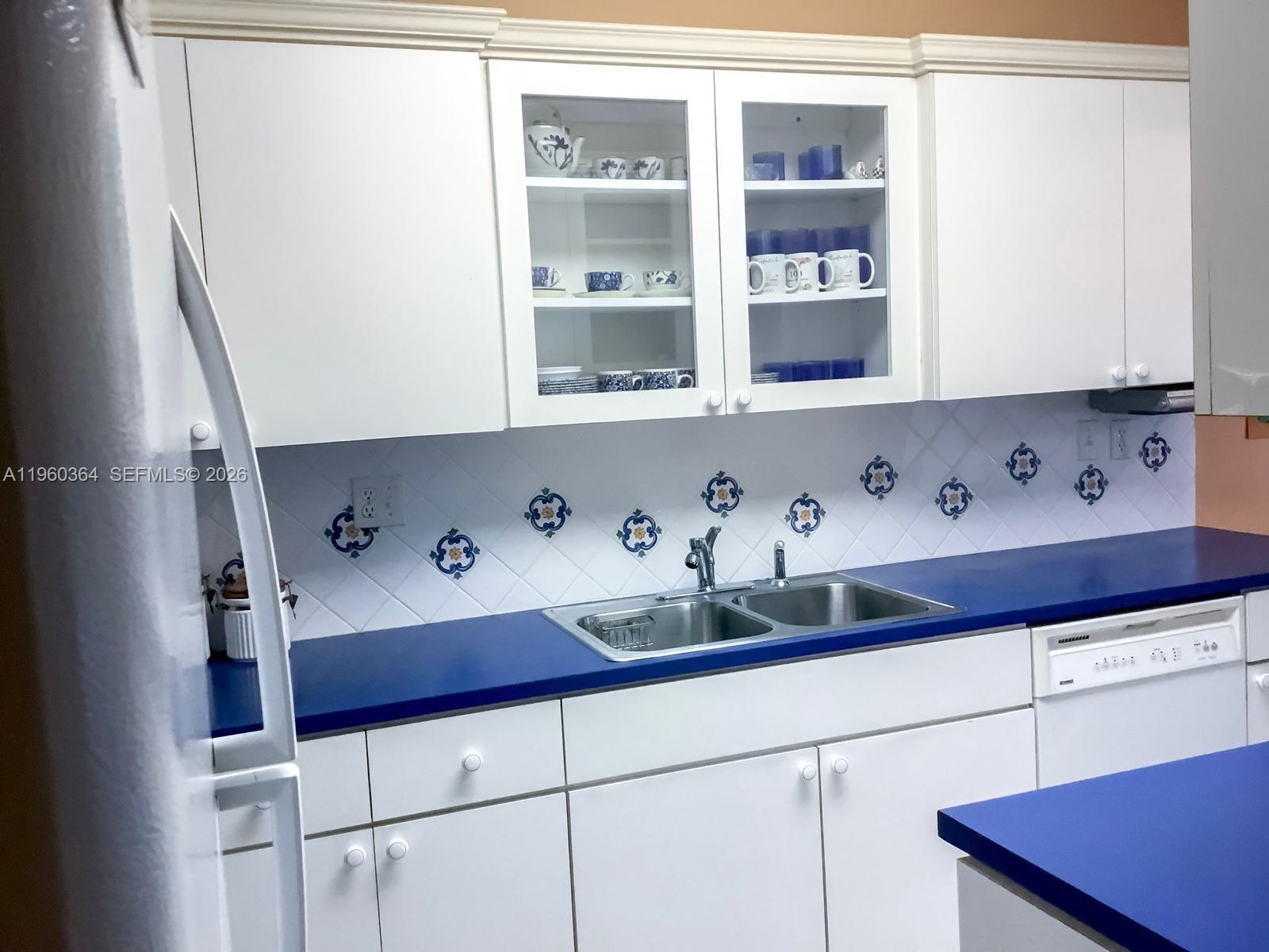 A kitchen features white cabinets, blue countertops, a double sink, and a tiled backsplash — 5800 SW 127th Ave # 2220, Miami FL 33183, MIAMI, FL
