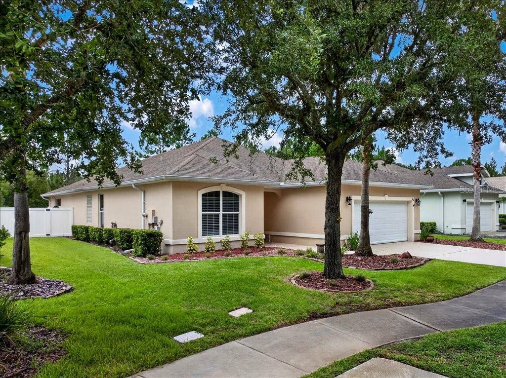 A single-story tan house with a two-car garage and a landscaped front yard — 63 WESTLAND RUN, ORMOND BEACH, FL