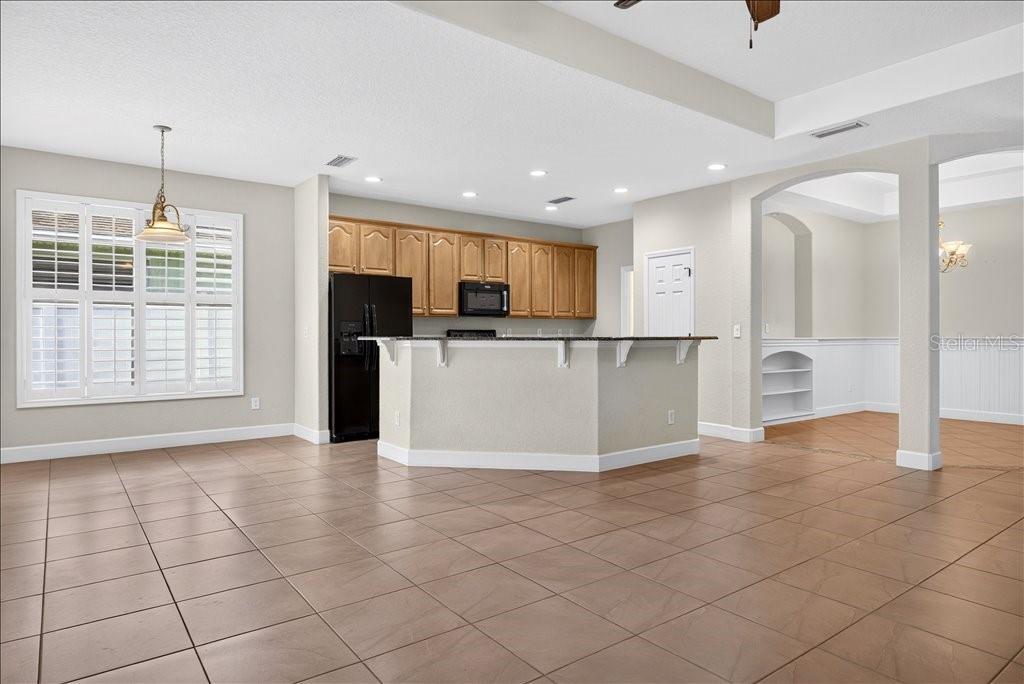 A kitchen with light wood cabinets, a black refrigerator, and a central island with seating — 63 WESTLAND RUN, ORMOND BEACH, FL