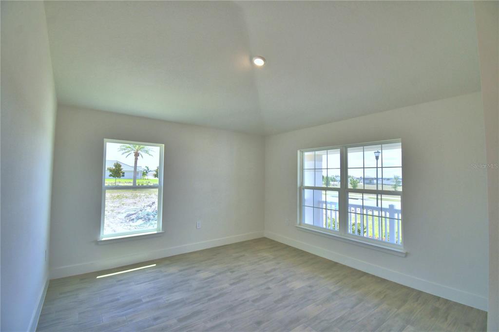 An empty room features light-colored wood-look flooring, white walls, and two large windows — 5250 TENNESSEE RIDGE COURT, AUBURNDALE, FL