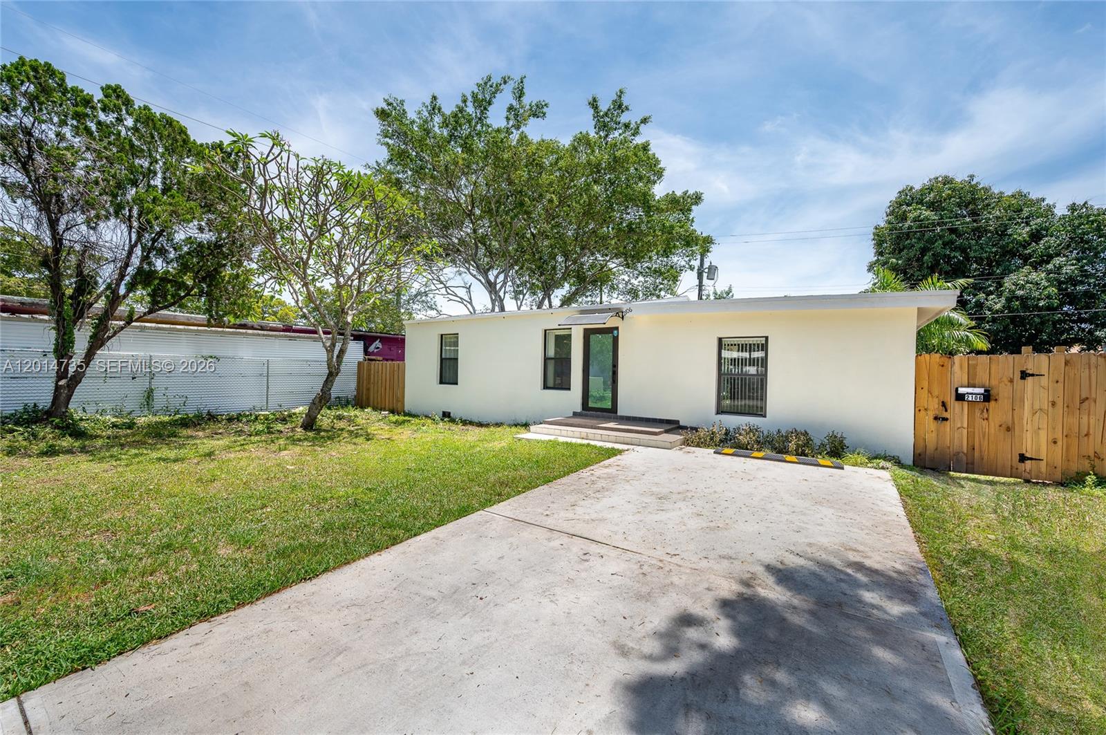 A single-story house with a concrete driveway and a wooden fence stands in a yard — 2106 Plunkett Ct, Hollywood FL 33020, HOLLYWOOD, FL