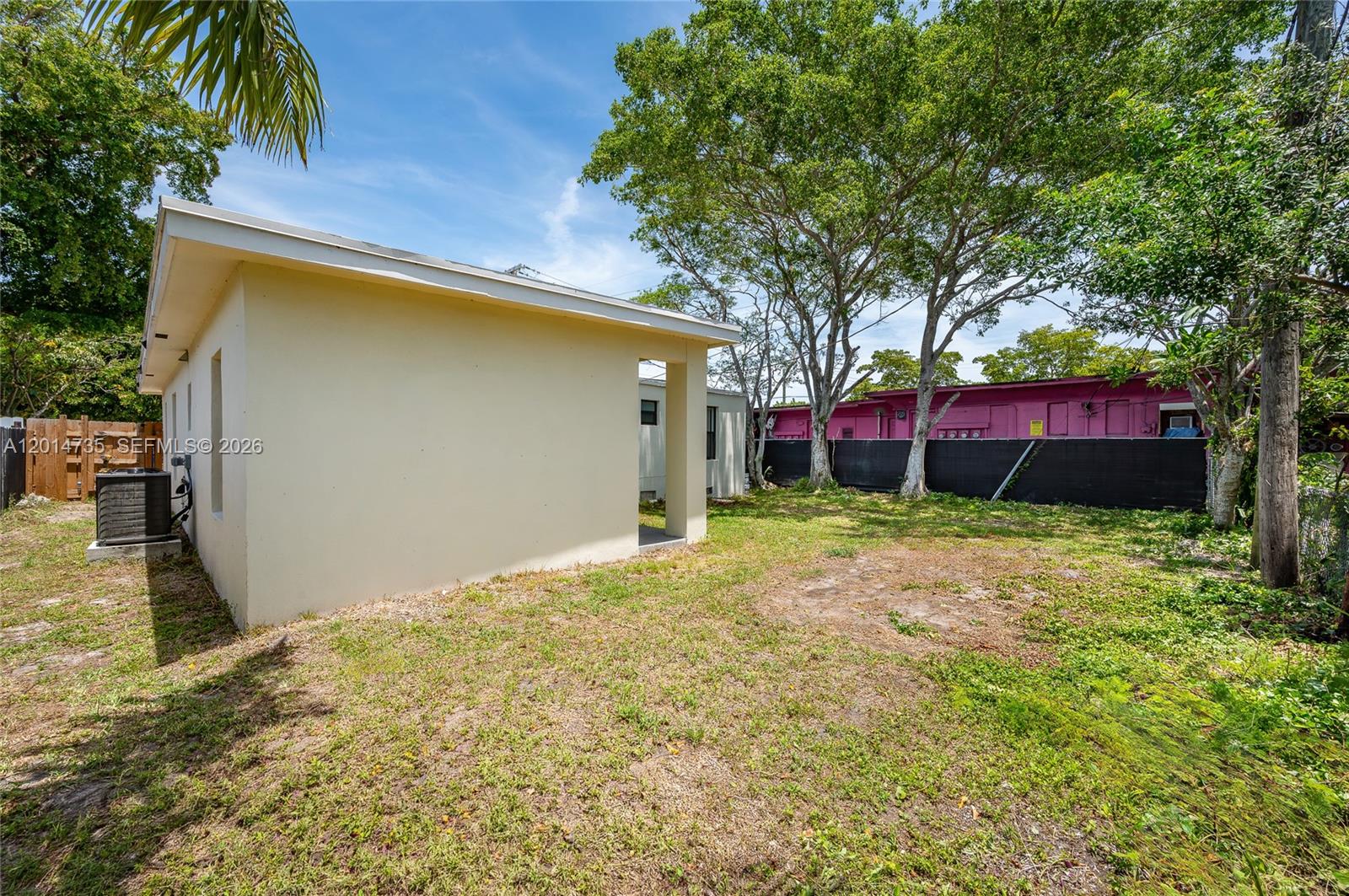 A side view of a light-colored house with a small yard and a black fence — 2106 Plunkett Ct, Hollywood FL 33020, HOLLYWOOD, FL
