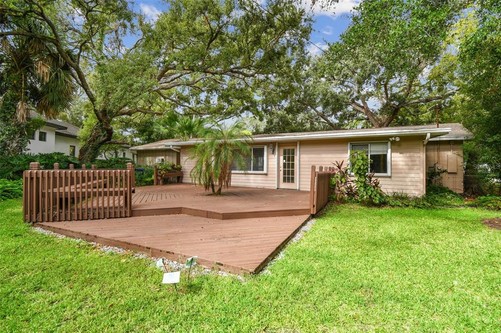 A single-story house with light-colored siding features a large wooden deck in the backyard — 4508 HENDERSON BOULEVARD, TAMPA, FL