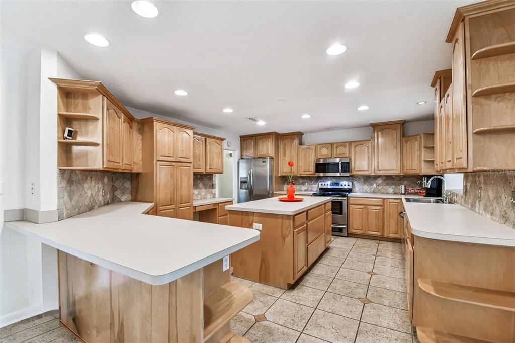 A kitchen features light wood cabinets, a central island, and light-colored countertops — 4508 HENDERSON BOULEVARD, TAMPA, FL