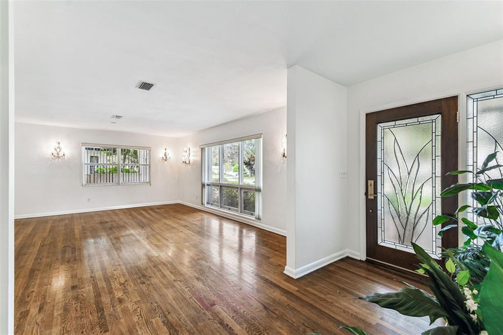 An empty living room features hardwood floors, white walls, and a decorative glass front door — 4508 HENDERSON BOULEVARD, TAMPA, FL