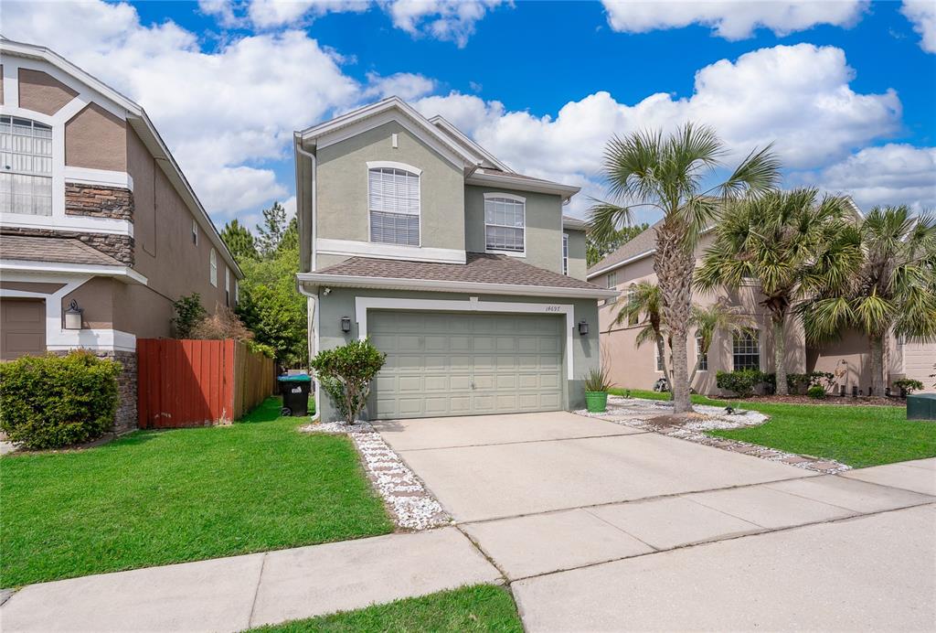 A two-story suburban house with a light green exterior and a two-car garage — 14697 HUNTCLIFF PARK WAY, ORLANDO, FL