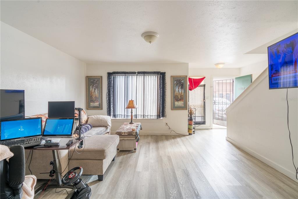 A living room with light wood-look flooring, a sofa, a computer desk, and a staircase — 4004 BARWOOD DRIVE UNIT 3804, ORLANDO, FL