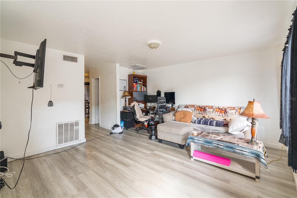A living room features light wood-look flooring, a sectional sofa, and a desk workspace — 4004 BARWOOD DRIVE UNIT 3804, ORLANDO, FL