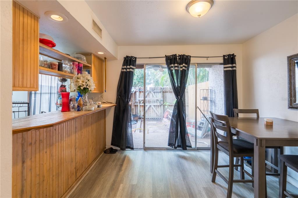A dining area features a wooden bar, sliding glass doors, and a table with chairs — 4004 BARWOOD DRIVE UNIT 3804, ORLANDO, FL