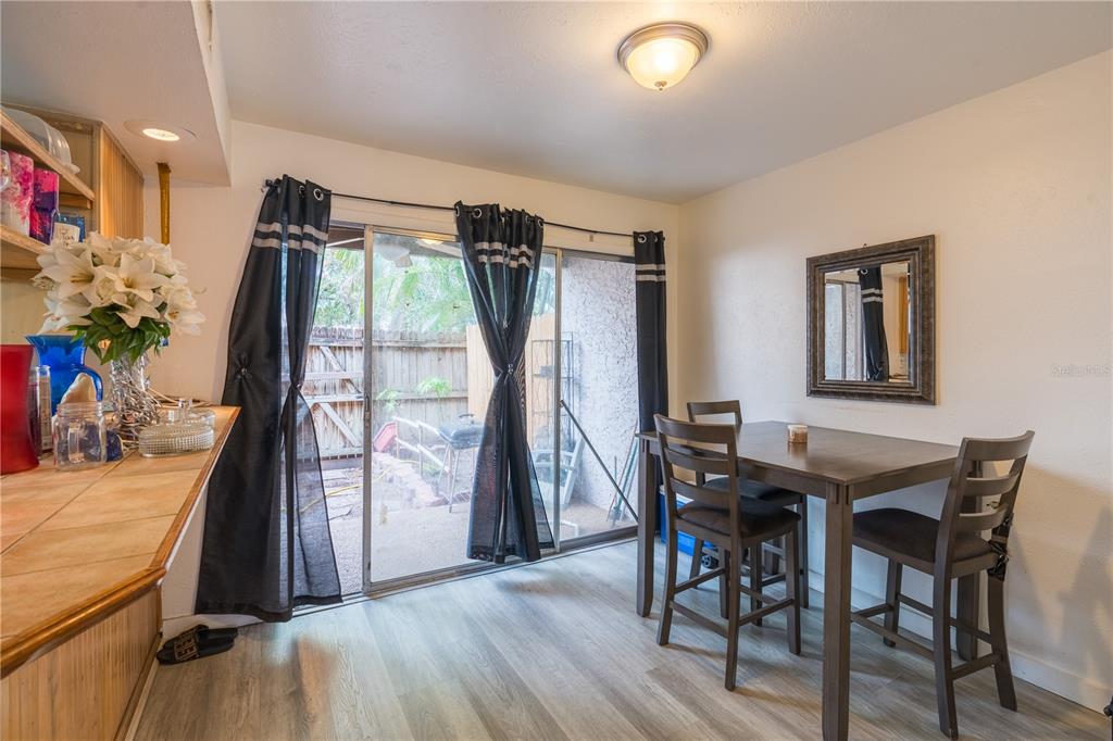 A dining area features a wooden table, chairs, sliding glass doors, and light wood-look flooring — 4004 BARWOOD DRIVE UNIT 3804, ORLANDO, FL