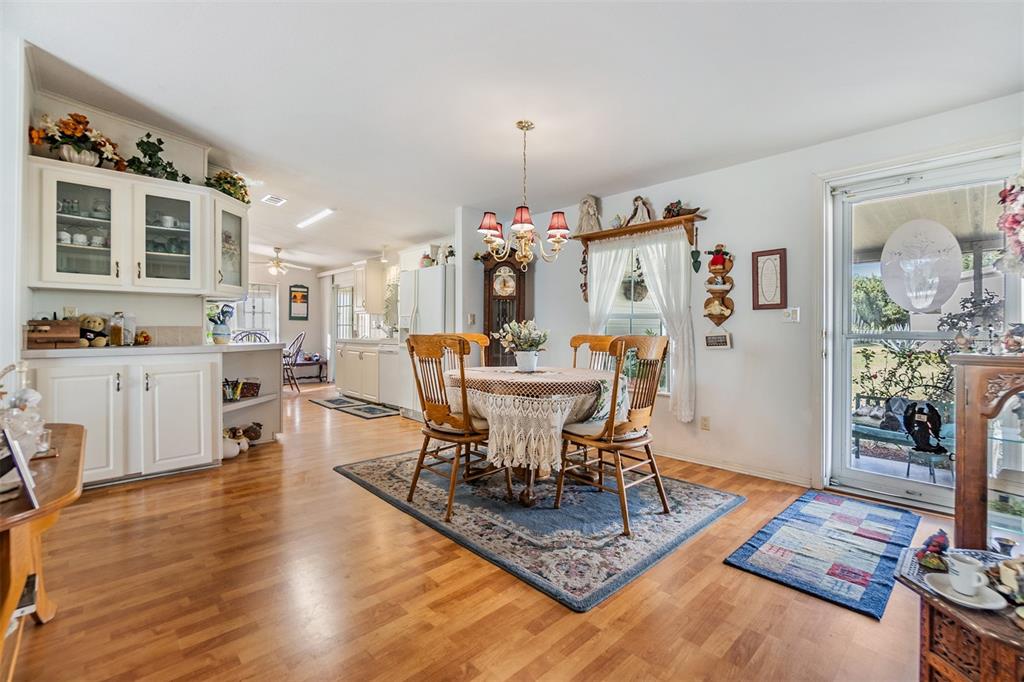 A dining area with a round table, wooden chairs, and white cabinetry on hardwood floors — 37340 NEUKOM AVENUE, ZEPHYRHILLS, FL