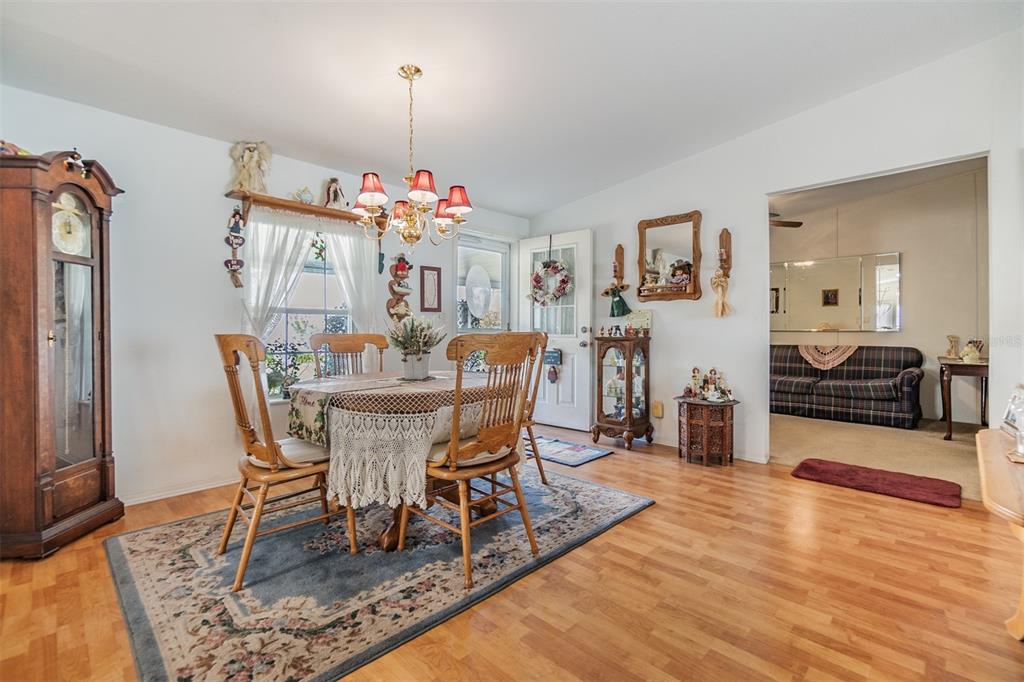 A dining room with a wooden table, chairs, a grandfather clock, and hardwood flooring — 37340 NEUKOM AVENUE, ZEPHYRHILLS, FL