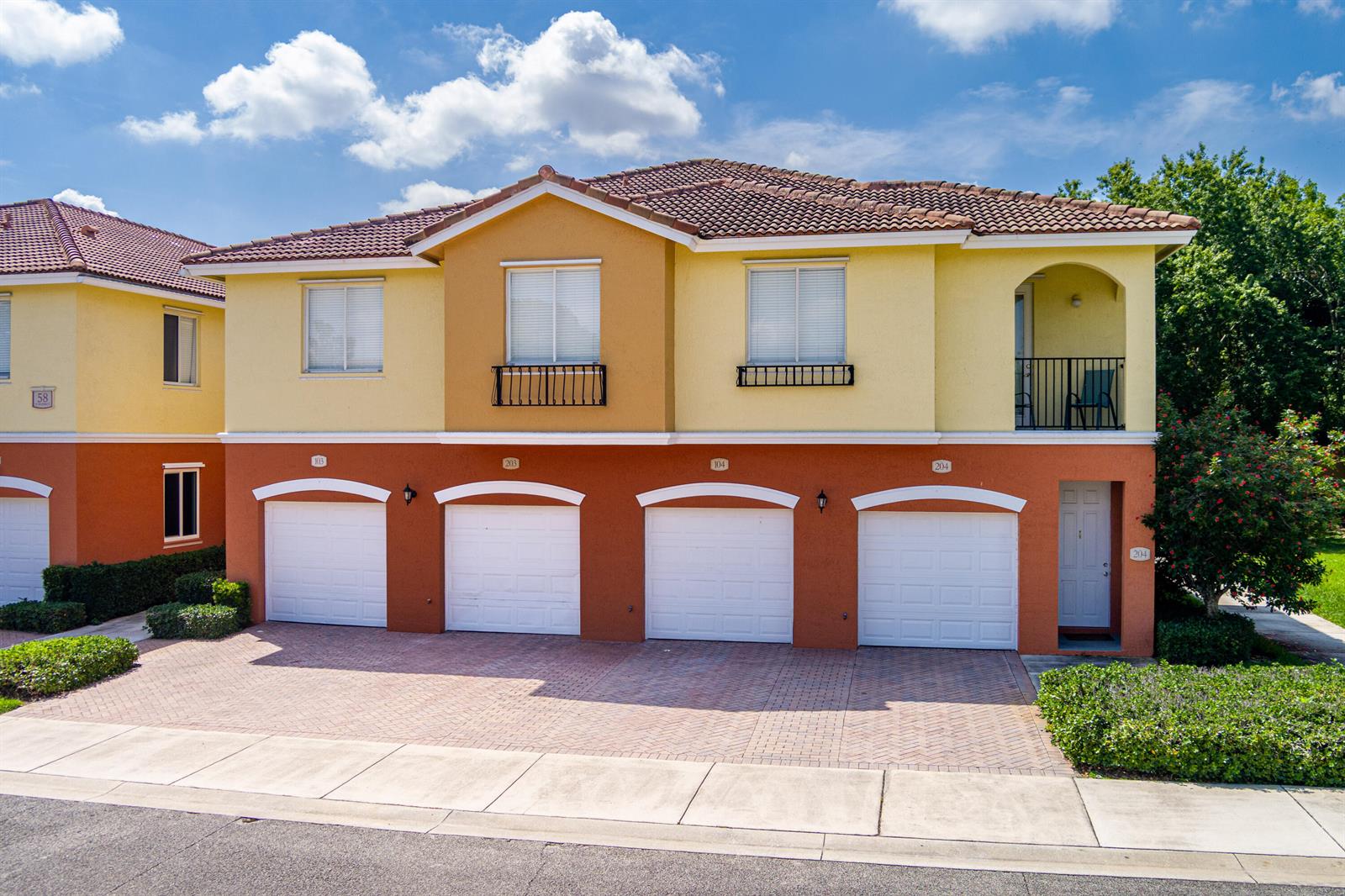 A two-story building features four garage doors, stucco walls, and a tiled roof — 58 SE Palermo Court # 104, Stuart FL 34994, STUART, FL