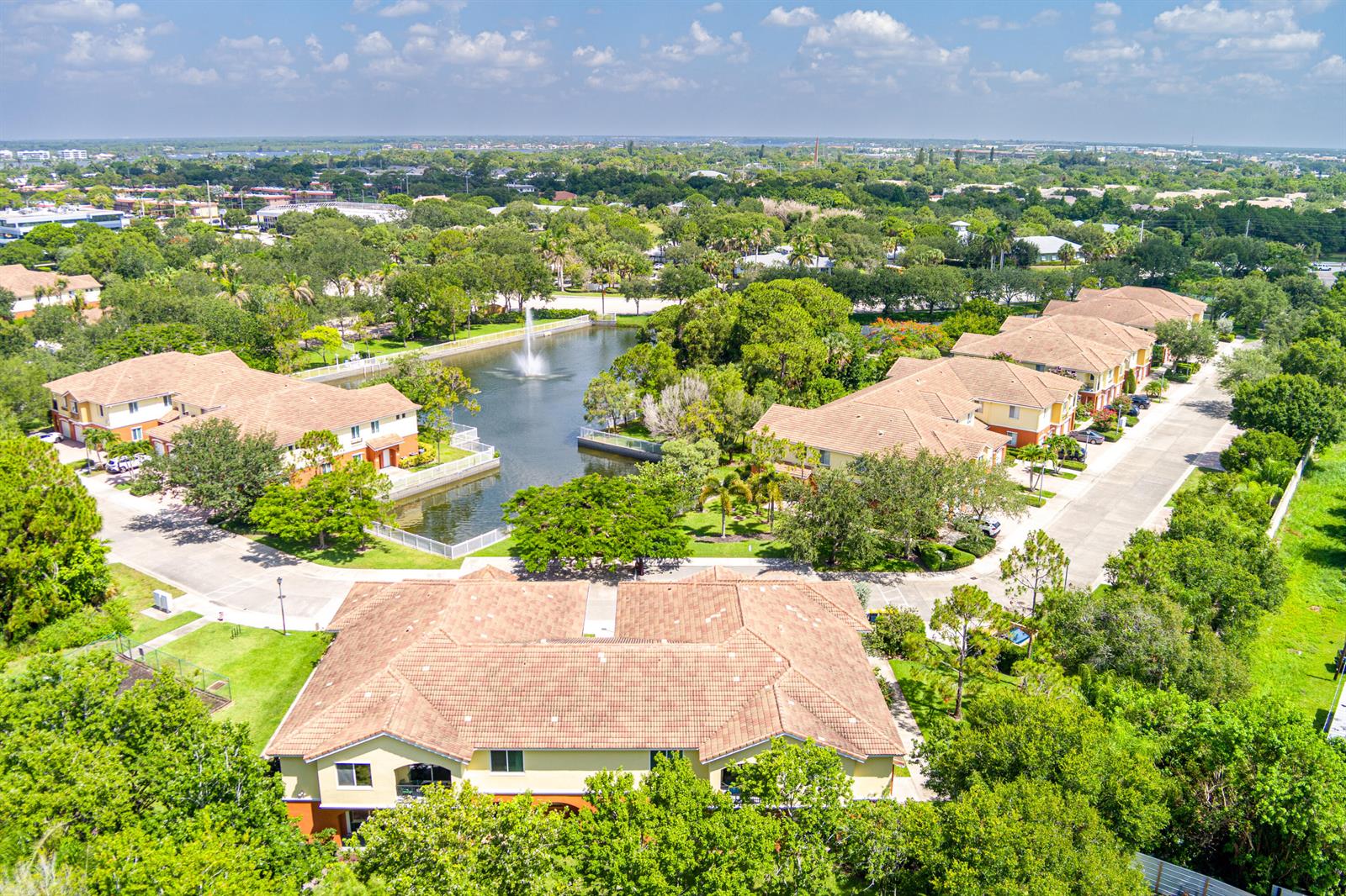 An aerial view of a residential complex with multiple buildings surrounding a central pond fountain — 58 SE Palermo Court # 104, Stuart FL 34994, STUART, FL