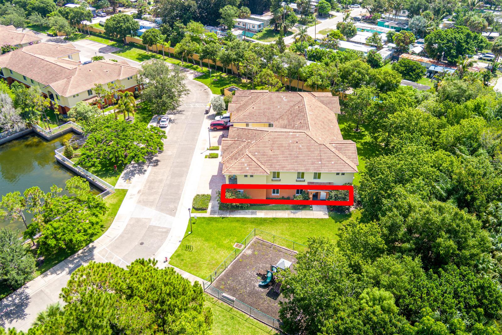 An aerial view shows the exterior of a multi-story apartment building with a red-outlined ground floor — 58 SE Palermo Court # 104, Stuart FL 34994, STUART, FL