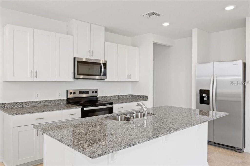 A kitchen with white cabinets, granite countertops, a center island, and stainless steel appliances — 1361 CURRENT PLACE, HAINES CITY, FL