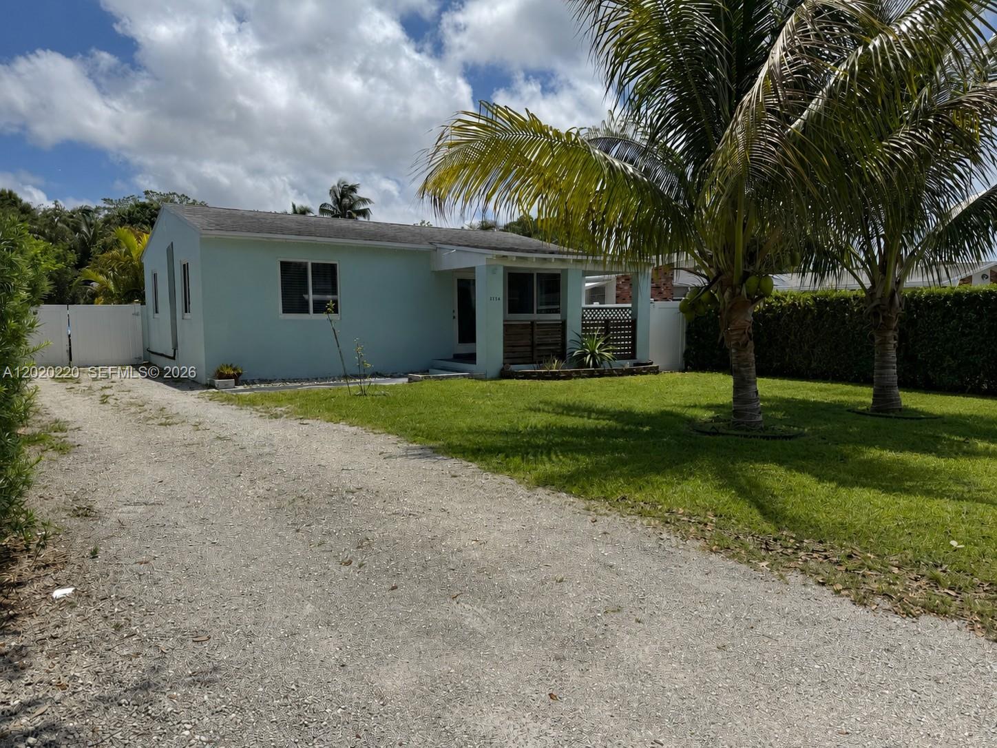 A light blue single-story house features a gravel driveway and two palm trees in front — 2726 Taylor St, Hollywood FL 33020, HOLLYWOOD, FL