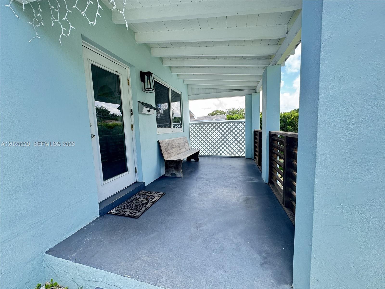 A covered porch features a light blue exterior, a wooden bench, and a dark floor — 2726 Taylor St, Hollywood FL 33020, HOLLYWOOD, FL
