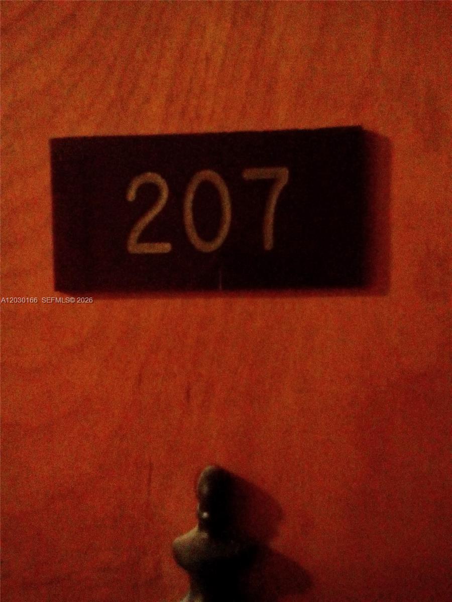 A black sign with the number 207 is mounted on a textured orange door — 13390 NE 7th Ave # 207, North Miami FL 33161, NORTH MIAMI, FL