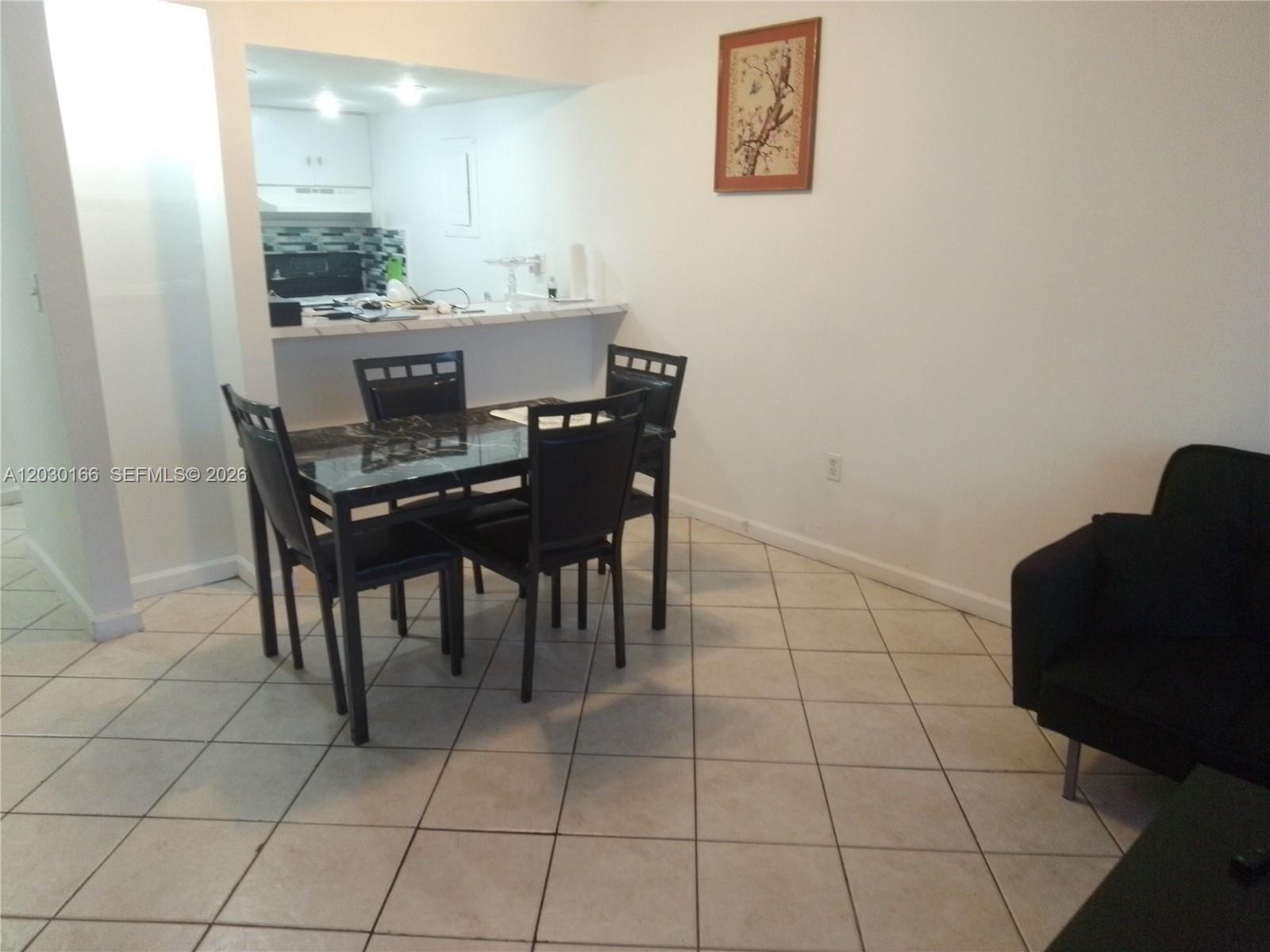 A dining area features a dark table with four chairs and tiled flooring — 13390 NE 7th Ave # 207, North Miami FL 33161, NORTH MIAMI, FL