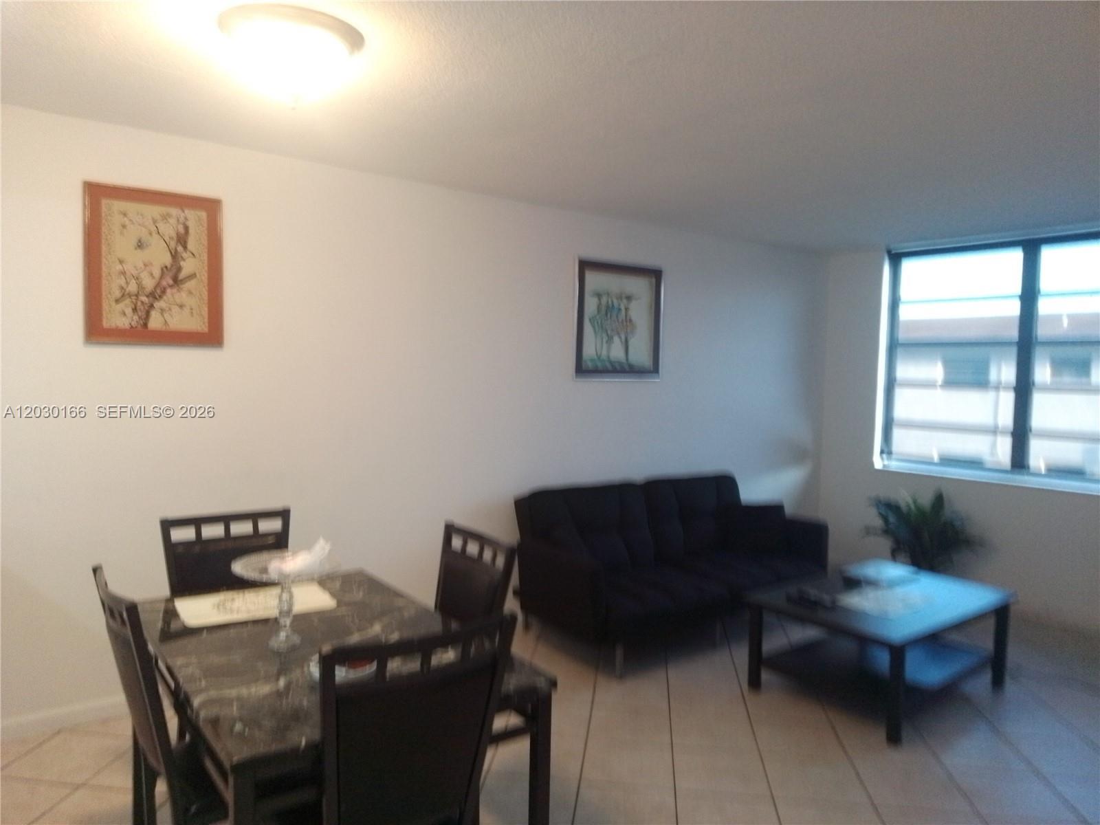 A living and dining area features tile flooring, a dark sofa, and a dining set — 13390 NE 7th Ave # 207, North Miami FL 33161, NORTH MIAMI, FL