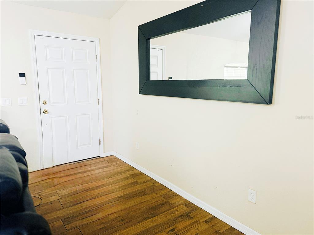 A room with wood-look flooring, a white door, and a large mirror on the wall — 36 WALNUT COURSE, OCALA, FL