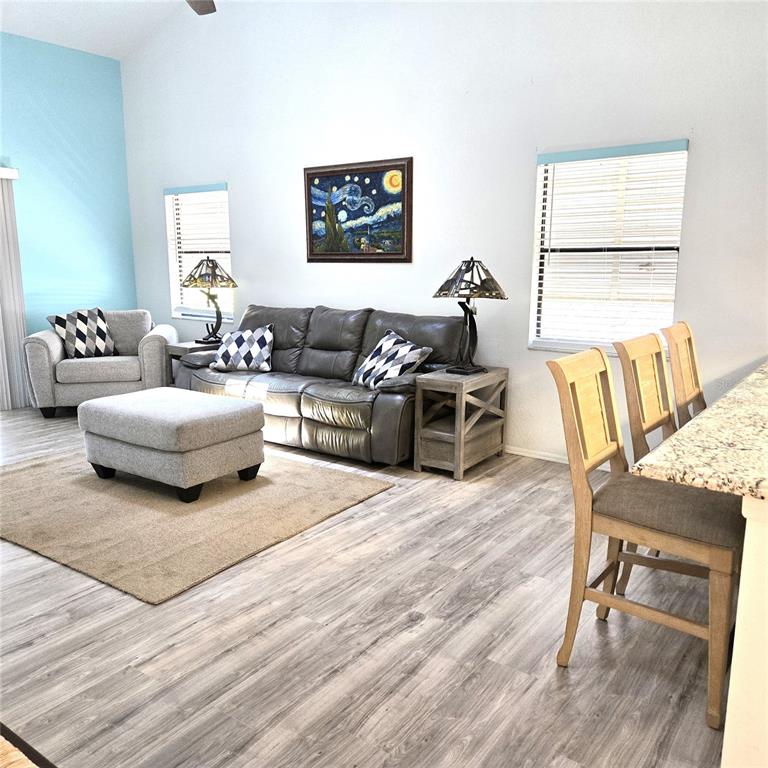 A living room features a grey sofa, matching armchair, ottoman, and a breakfast bar — 302 40TH STREET CIRCLE W, PALMETTO, FL