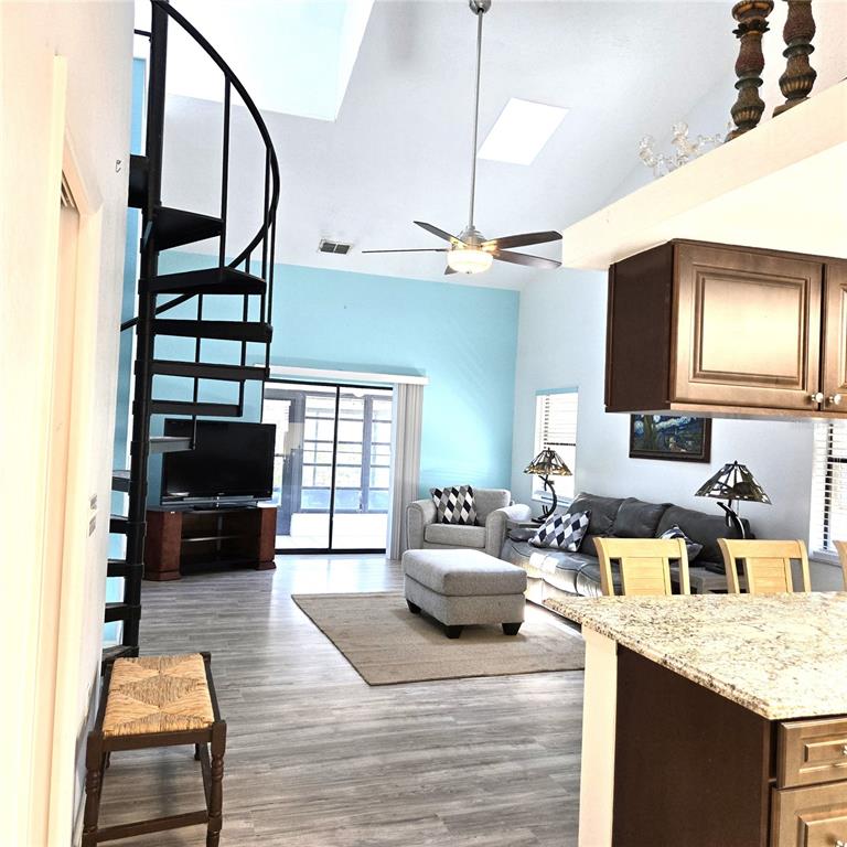 A living room features a spiral staircase, light blue walls, and a kitchen island — 302 40TH STREET CIRCLE W, PALMETTO, FL