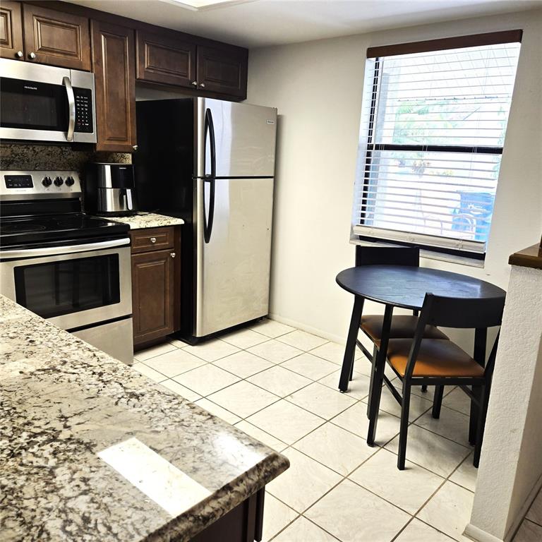 A kitchen features dark wood cabinets, granite countertops, stainless steel appliances, and a small dining table — 302 40TH STREET CIRCLE W, PALMETTO, FL