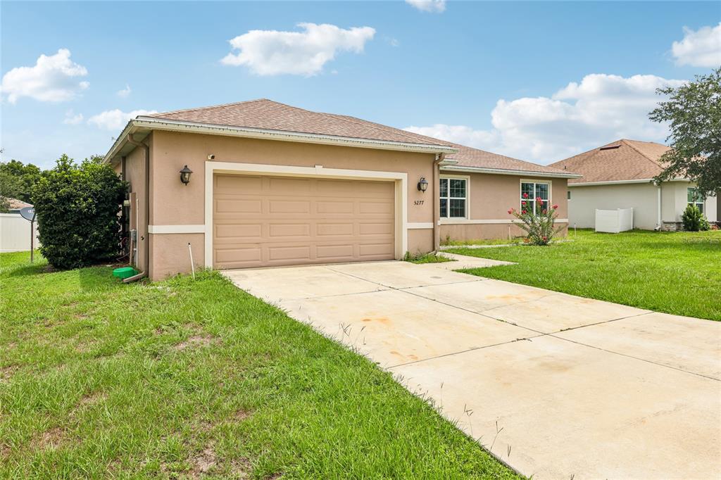 A tan single-story house with a two-car garage and a concrete driveway — 5277 SE 91ST PLACE, OCALA, FL