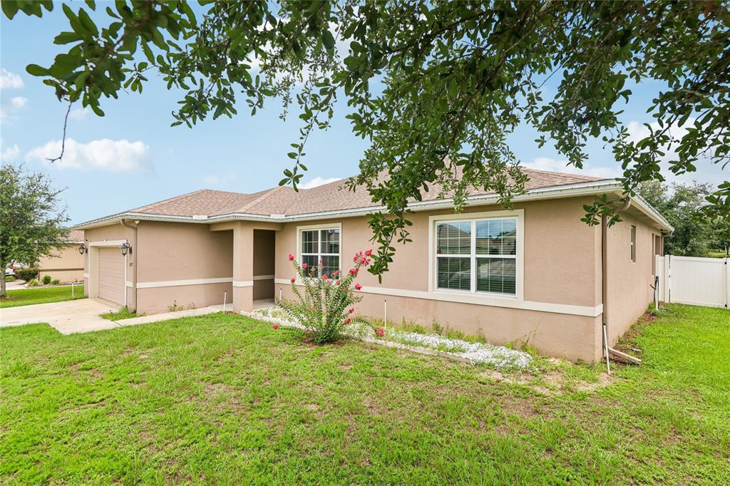 A single-story tan stucco house with a two-car garage and a front lawn — 5277 SE 91ST PLACE, OCALA, FL