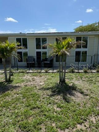 A light yellow mobile home with a screened-in porch and a carport sits on grass — 1 POINSETTIA DRIVE, FORT MYERS, FL