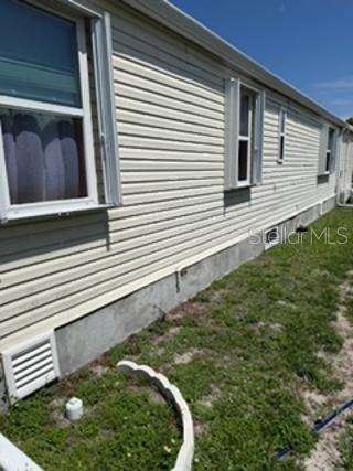 A side view of a light yellow manufactured home with a fenced patio area — 1 POINSETTIA DRIVE, FORT MYERS, FL
