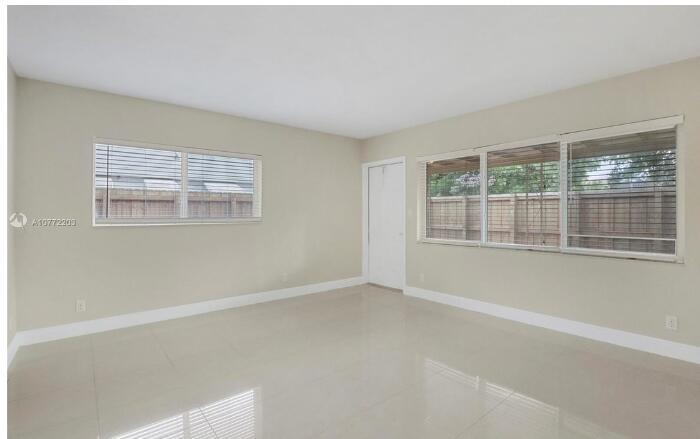 An empty room with light-colored tile floors, beige walls, and large windows with blinds — FORT LAUDERDALE, FL