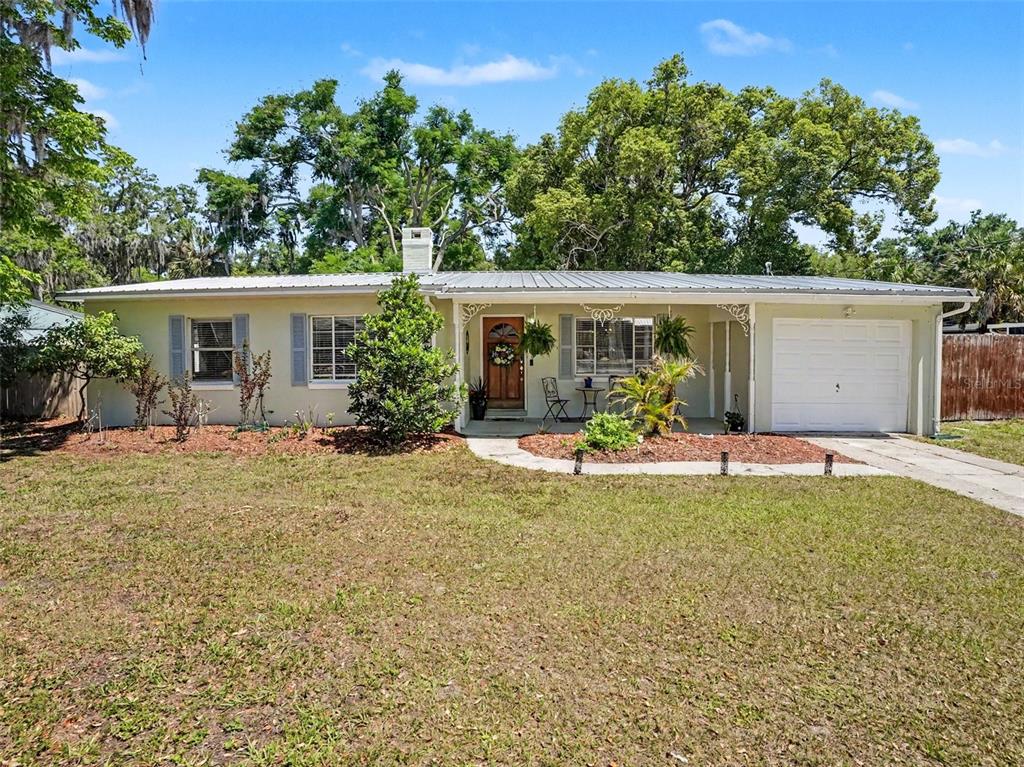 A single-story house with a metal roof, attached garage, and a front yard — 315 W 11TH AVENUE, MOUNT DORA, FL